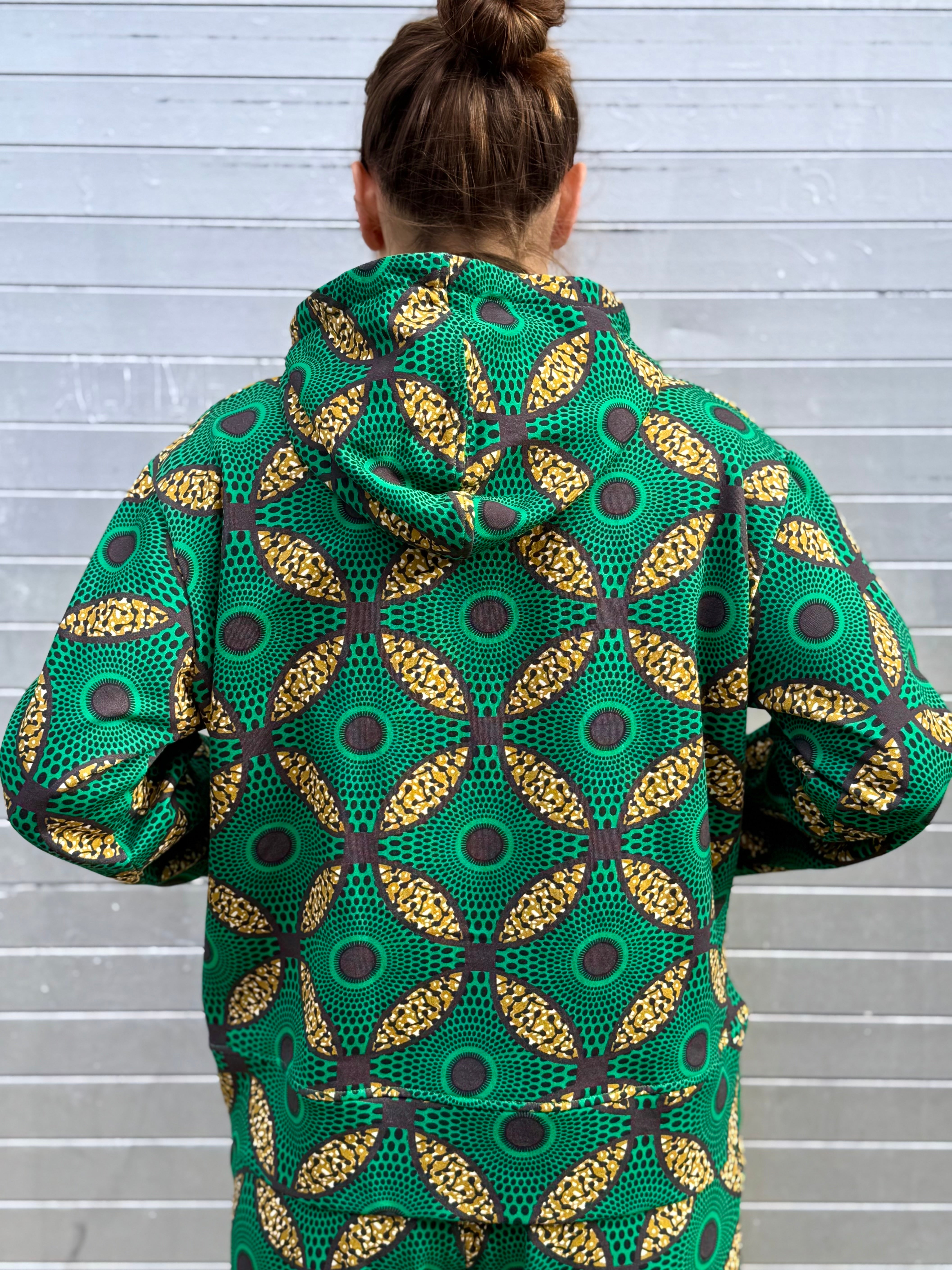 Rear angle of the Ìmọ́lẹ̀ Green Sweat Hoodie, featuring the iconic Yoruba geometric design in green and gold. Made with organic cotton and eco-friendly inks, it’s a soft statement of sustainability and cultural artistry.