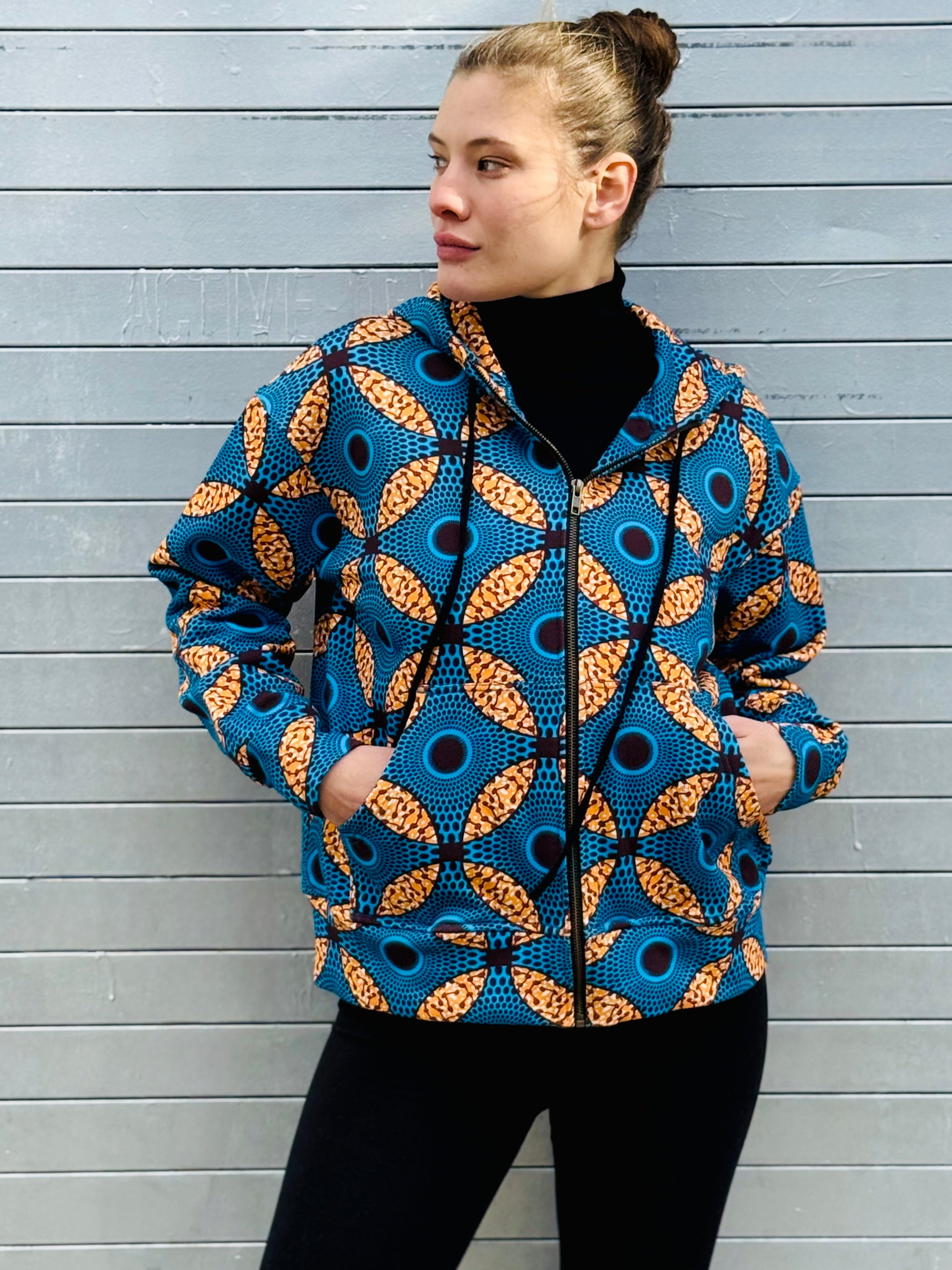 Model wearing the Ìmọ́lẹ̀ Blue Hoodie with hands in pockets, combining bold African-inspired design with casual sophistication. Made from organic cotton and printed with eco inks, this sustainable hoodie radiates warmth and empowerment.