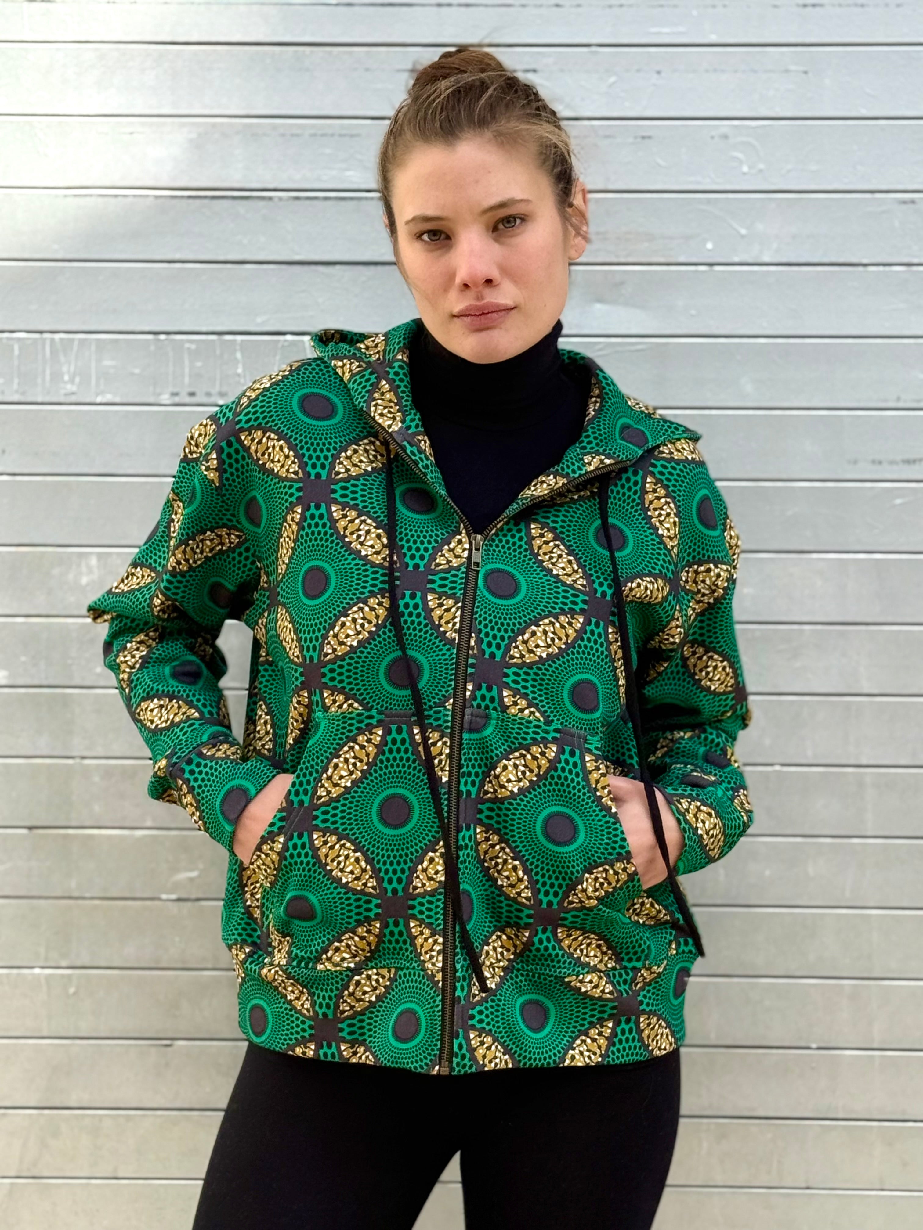 Front portrait of the Ìmọ́lẹ̀ Green Zip-Up Hoodie by Lola Faturoti Loves, crafted with organic cotton and eco inks. Its relaxed silhouette and artistic Yoruba pattern merge sustainable comfort with modern urban elegance.