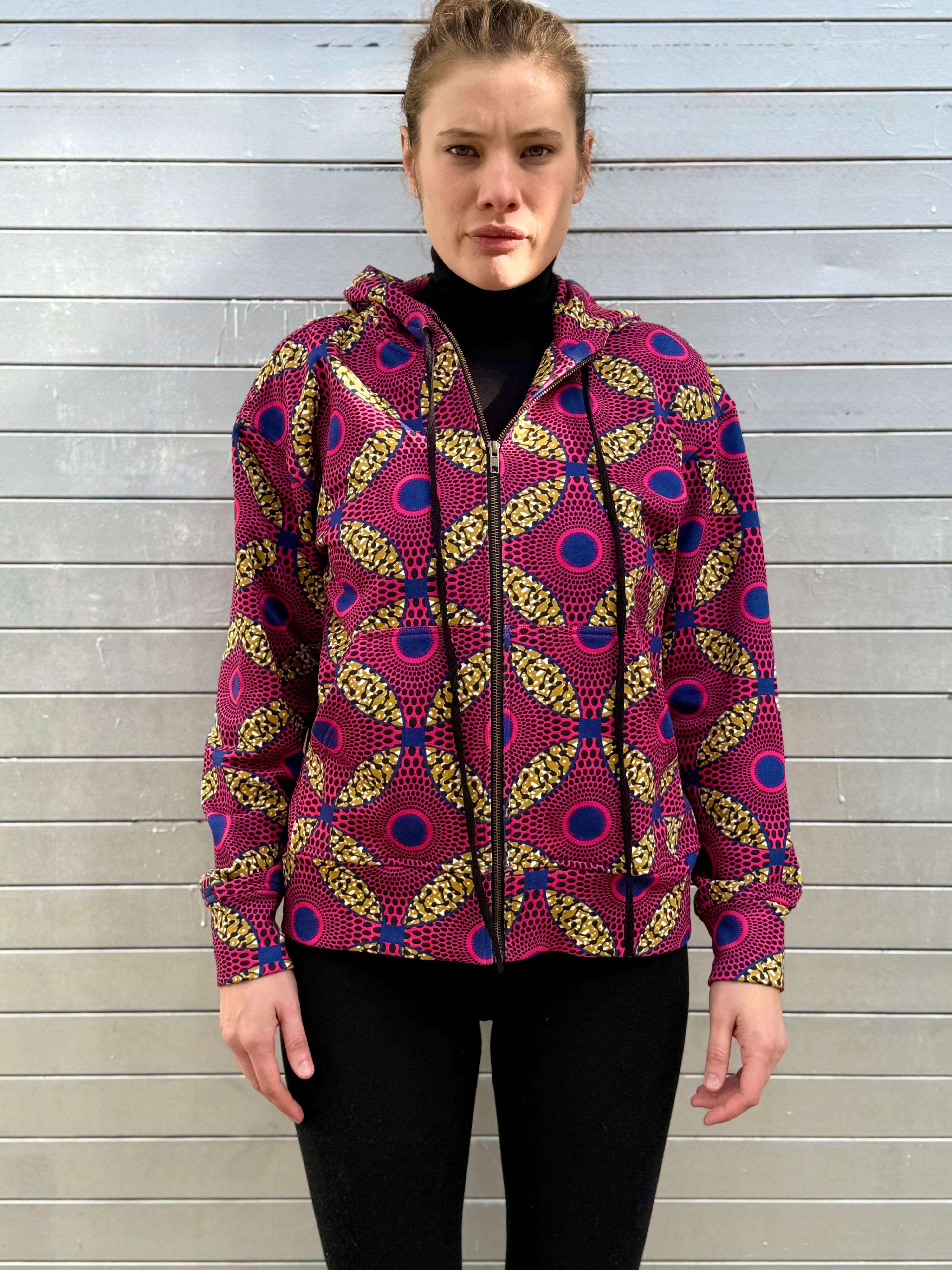 Model wearing the Ìmọ́lẹ̀ Pink Zip-Up Hoodie by Lola Faturoti Loves, crafted from organic cotton and printed with eco-friendly inks. The Yoruba-inspired pattern in magenta, gold, and navy brings vibrancy and warmth to winter, blending cultural storytelling with contemporary fashion.
Imole_zip_up_hoodie_pink
