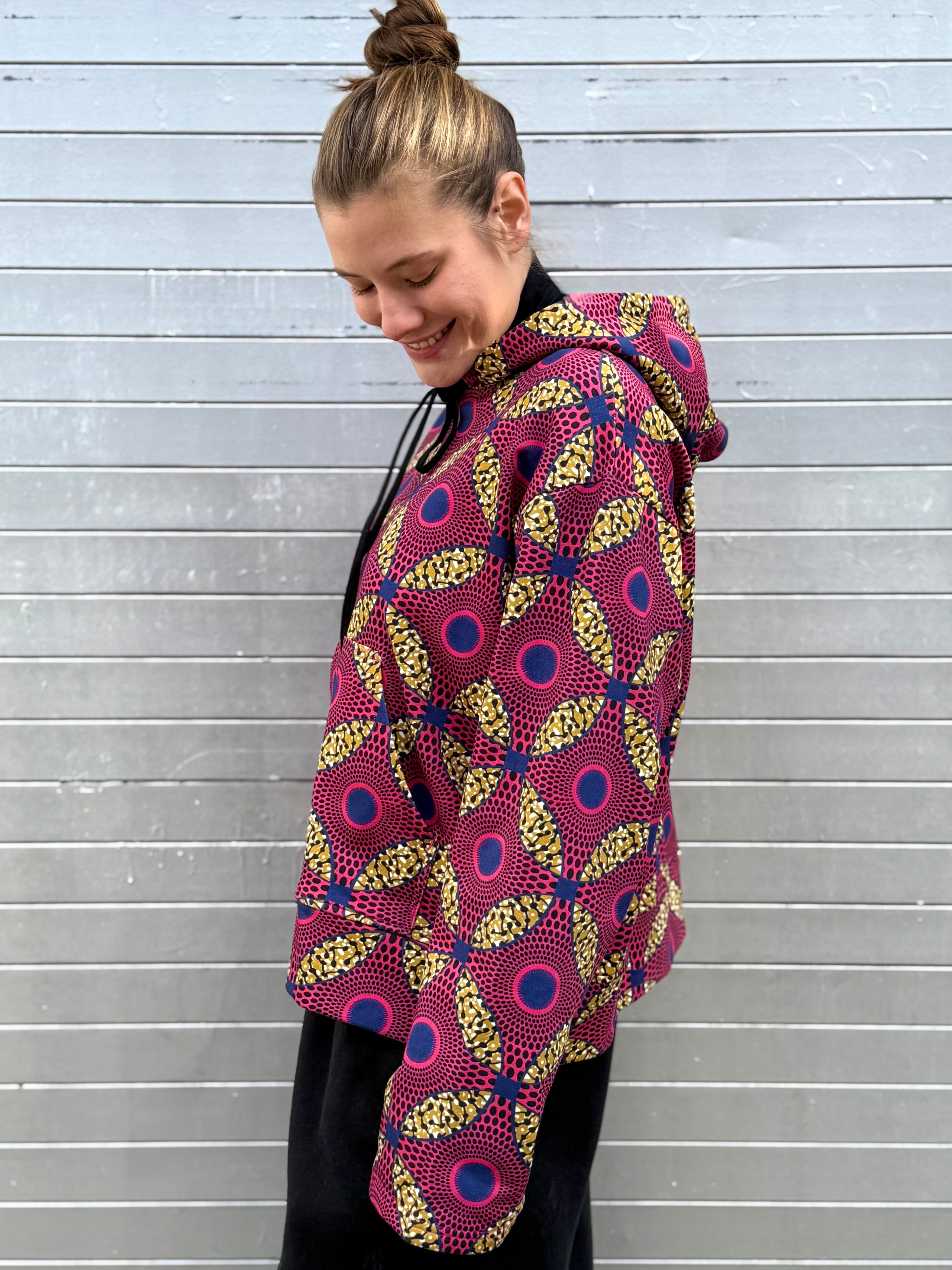 Side profile of the Ìmọ́lẹ̀ Pink Sweat Hoodie by Lola Faturoti Loves, capturing the lively pink and yellow geometric pattern. Made from soft organic cotton, it celebrates slow fashion, artisan craft, and the joyful power of color.