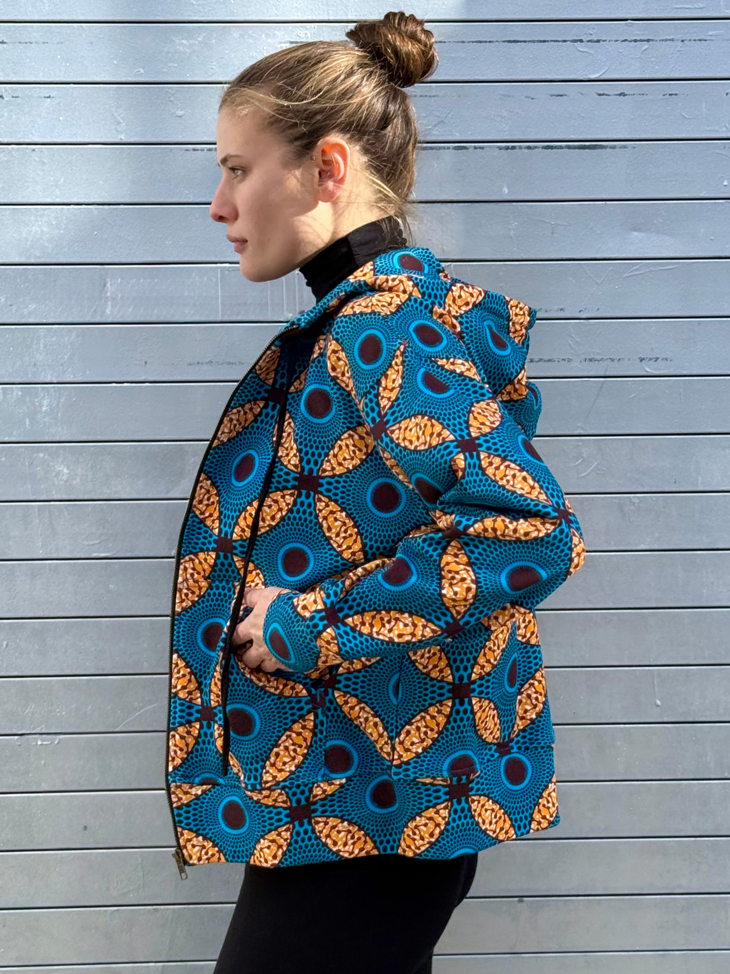 Side profile of model wearing the Ìmọ́lẹ̀ Blue Zip-Up Hoodie, showcasing its easy silhouette and geometric Yoruba print. Ethically made in India from organic cotton, this piece reflects Lola Faturoti Loves’ commitment to sustainable craftsmanship.