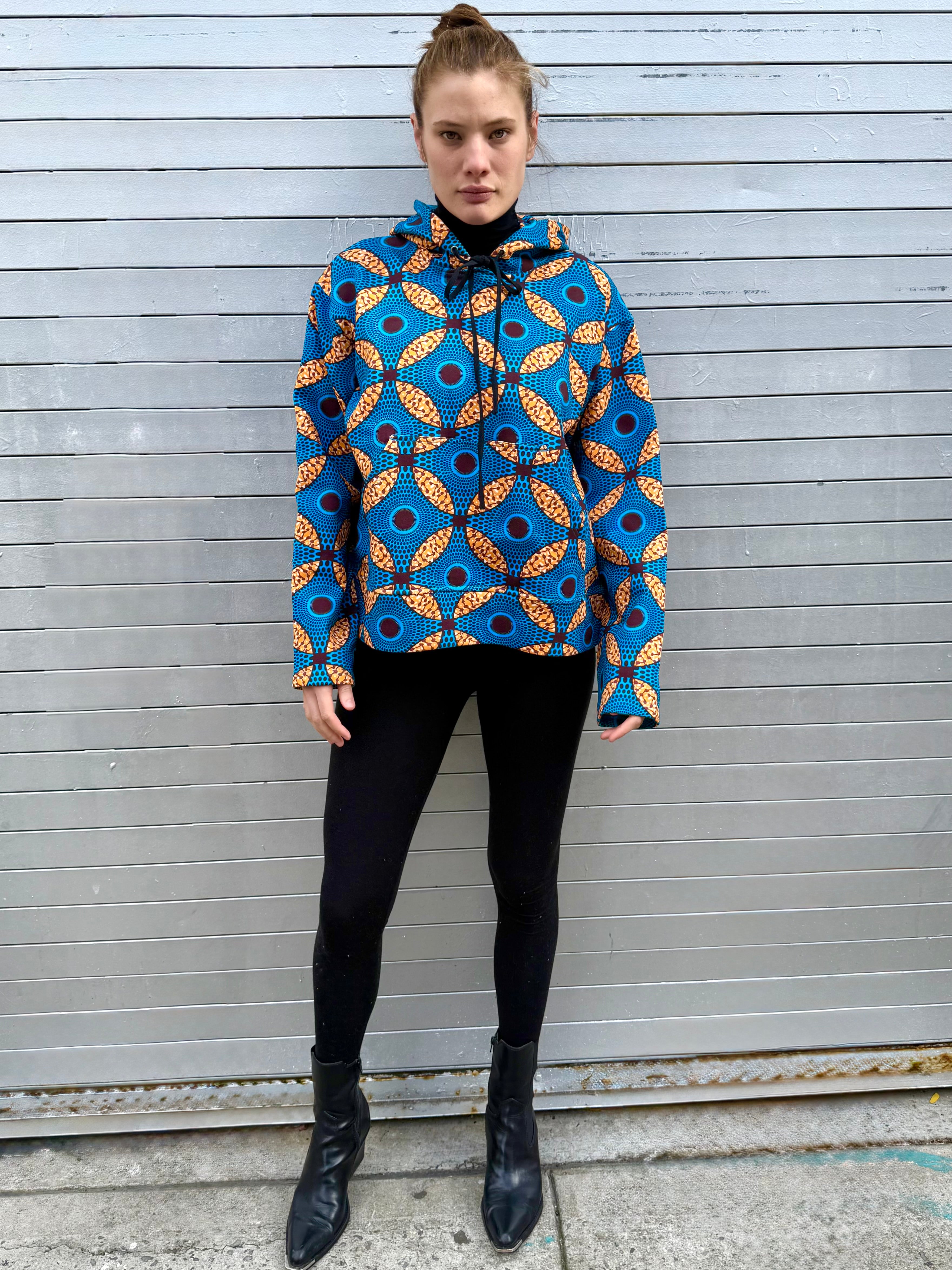 Full-body view of model wearing the Ìmọ́lẹ̀ Blue Sweat Hoodie by Lola Faturoti Loves. The geometric Yoruba-inspired pattern brings brightness to winter days, merging heritage design with modern comfort in a relaxed fit.