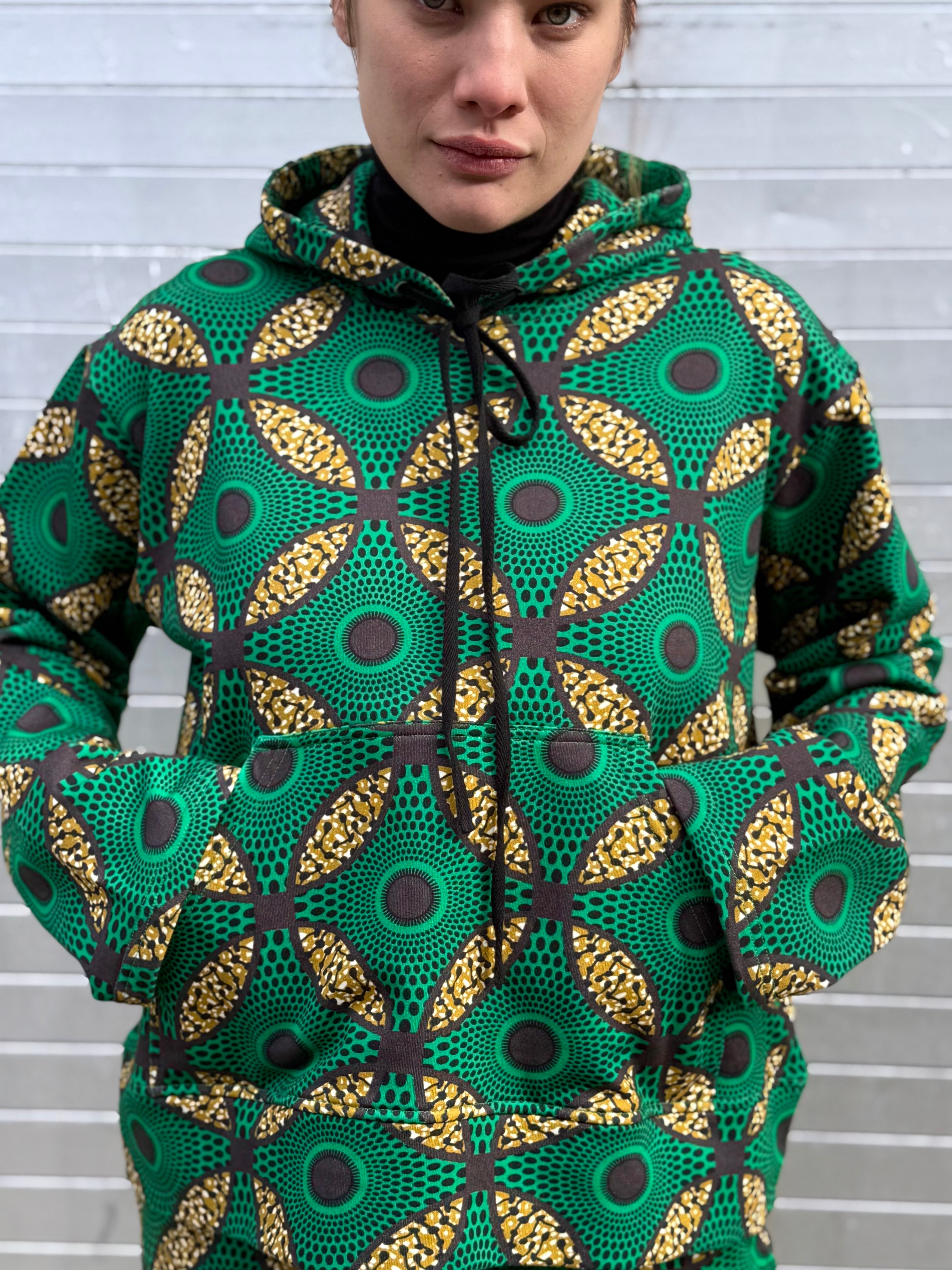 Close-up of the Ìmọ́lẹ̀ Green Sweat Hoodie by Lola Faturoti Loves, showcasing its radiant Yoruba motifs in green, black, and yellow. Ethically crafted in India, this piece represents empowerment through color, culture, and conscious fashion.