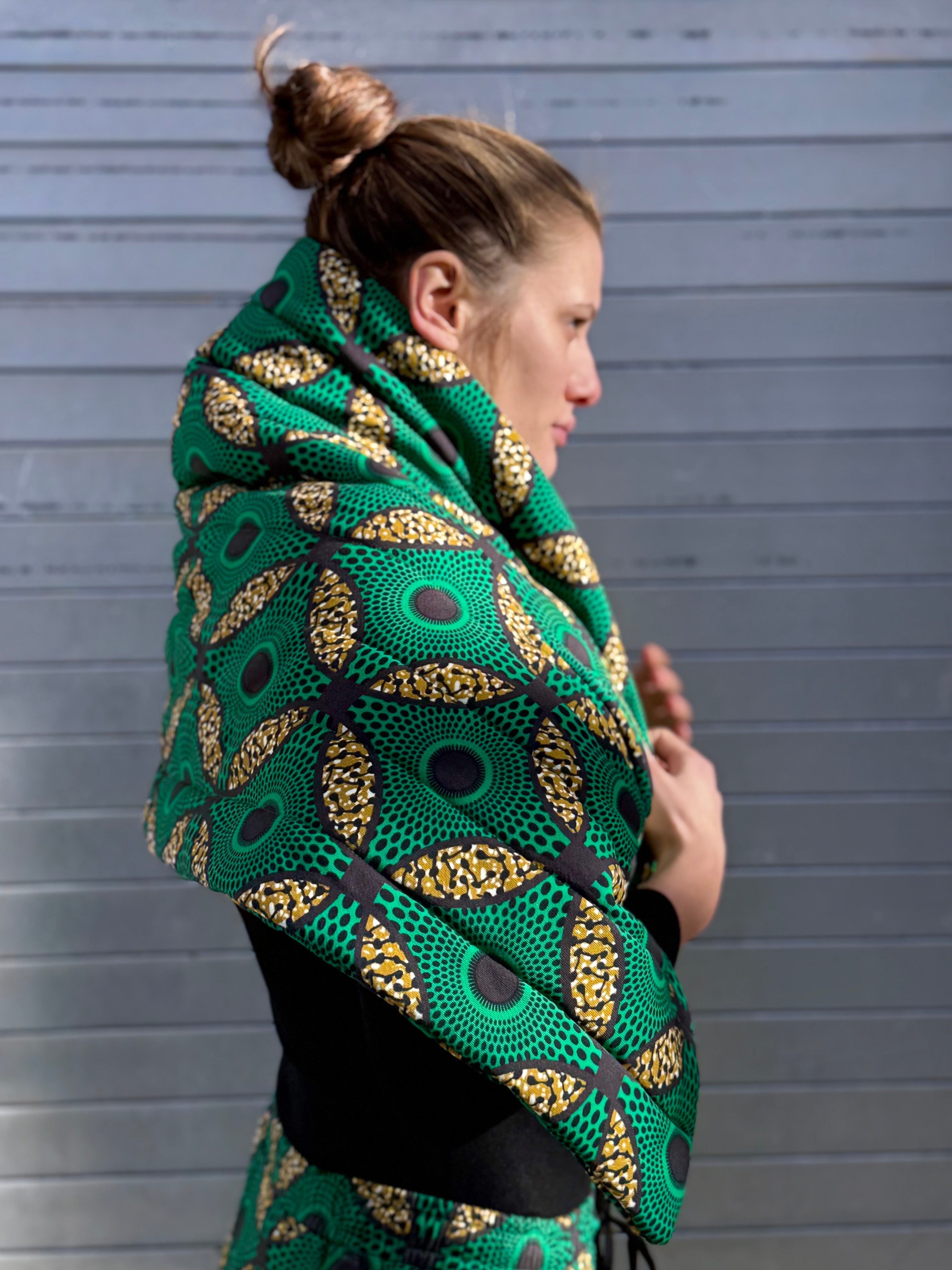 Side profile of the Ìmọ́lẹ̀ Green Scarf by Lola Faturoti Loves, sculptural and soft, featuring golden Yoruba motifs on green organic cotton for a sustainable modern look. Handcrafted in organic cotton, the Imole Green Scarf merges African artistry with contemporary design — sustainability, culture, and style in one piece.