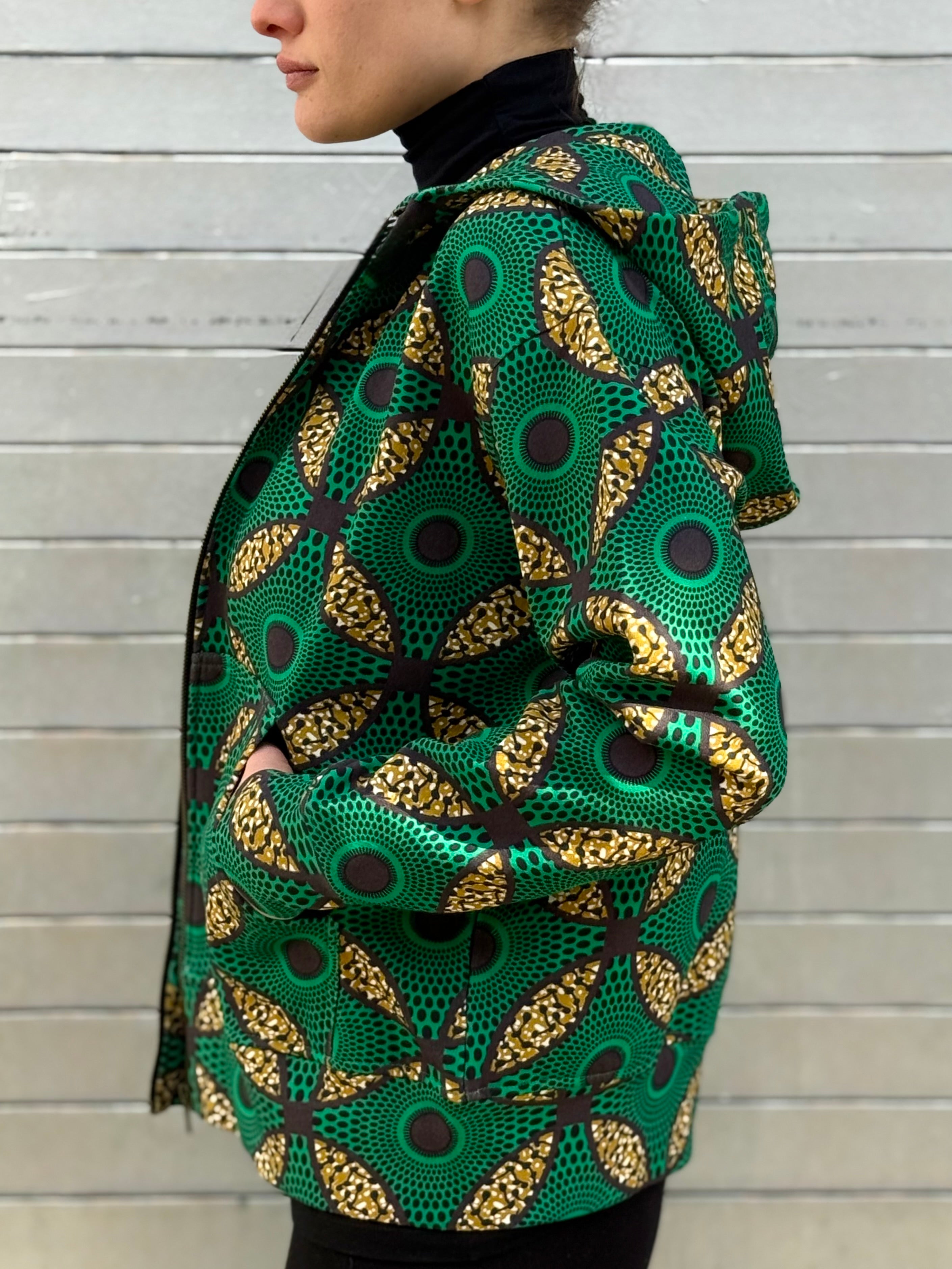 Side profile of the Ìmọ́lẹ̀ Green Hoodie by Lola Faturoti Loves, highlighting its bold geometric Yoruba print in green and yellow. Ethically made in India from organic cotton, this sustainable hoodie combines everyday comfort with artistic sophistication.