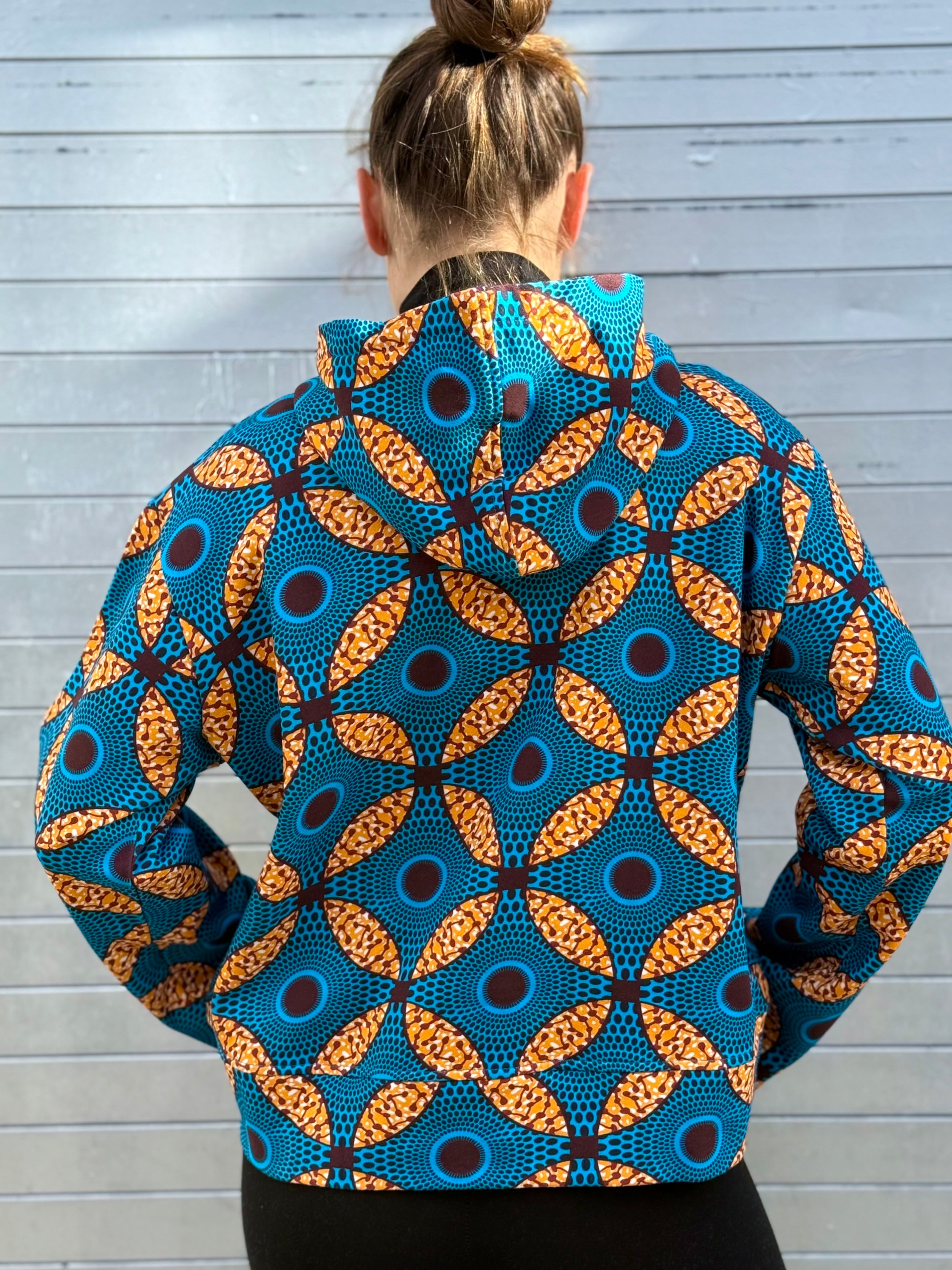 Back view of model wearing the Ìmọ́lẹ̀ Blue Sweat Hoodie by Lola Faturoti Loves. The symmetrical Yoruba motifs highlight the brand’s vision of unity and expression through color and form.