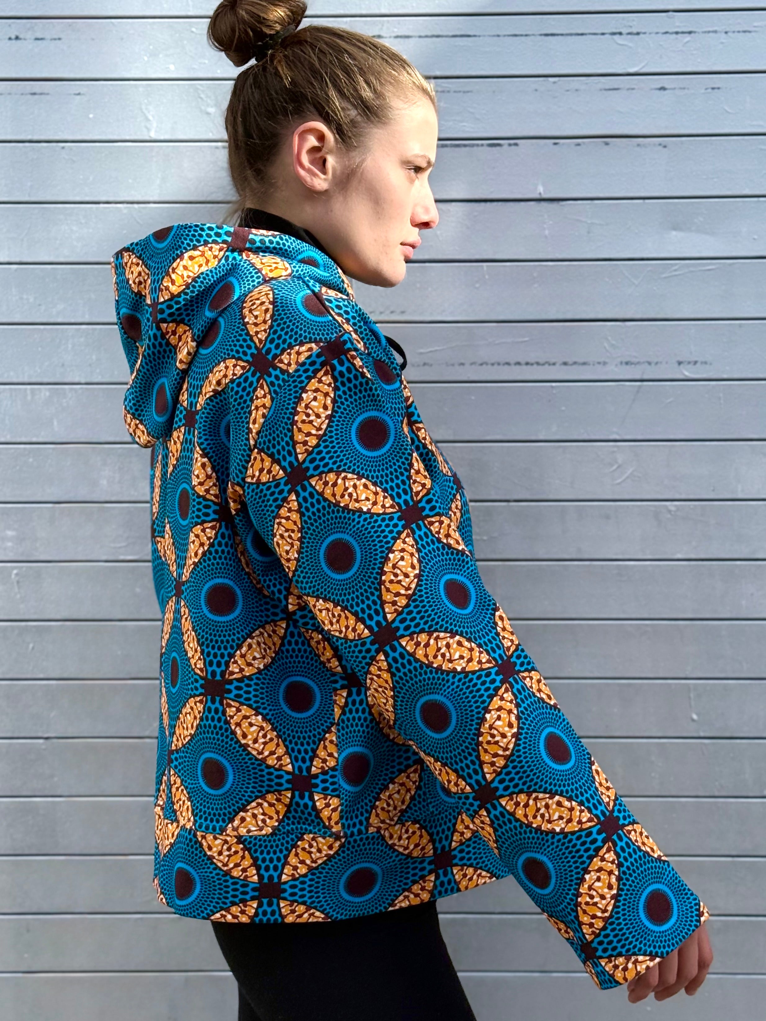 Side profile of the Ìmọ́lẹ̀ Blue Hoodie by Lola Faturoti Loves, showing its soft A-line sleeve and radiant Yoruba print. Made from organic cotton, this limited-edition piece celebrates cultural craftsmanship and sustainable luxury.