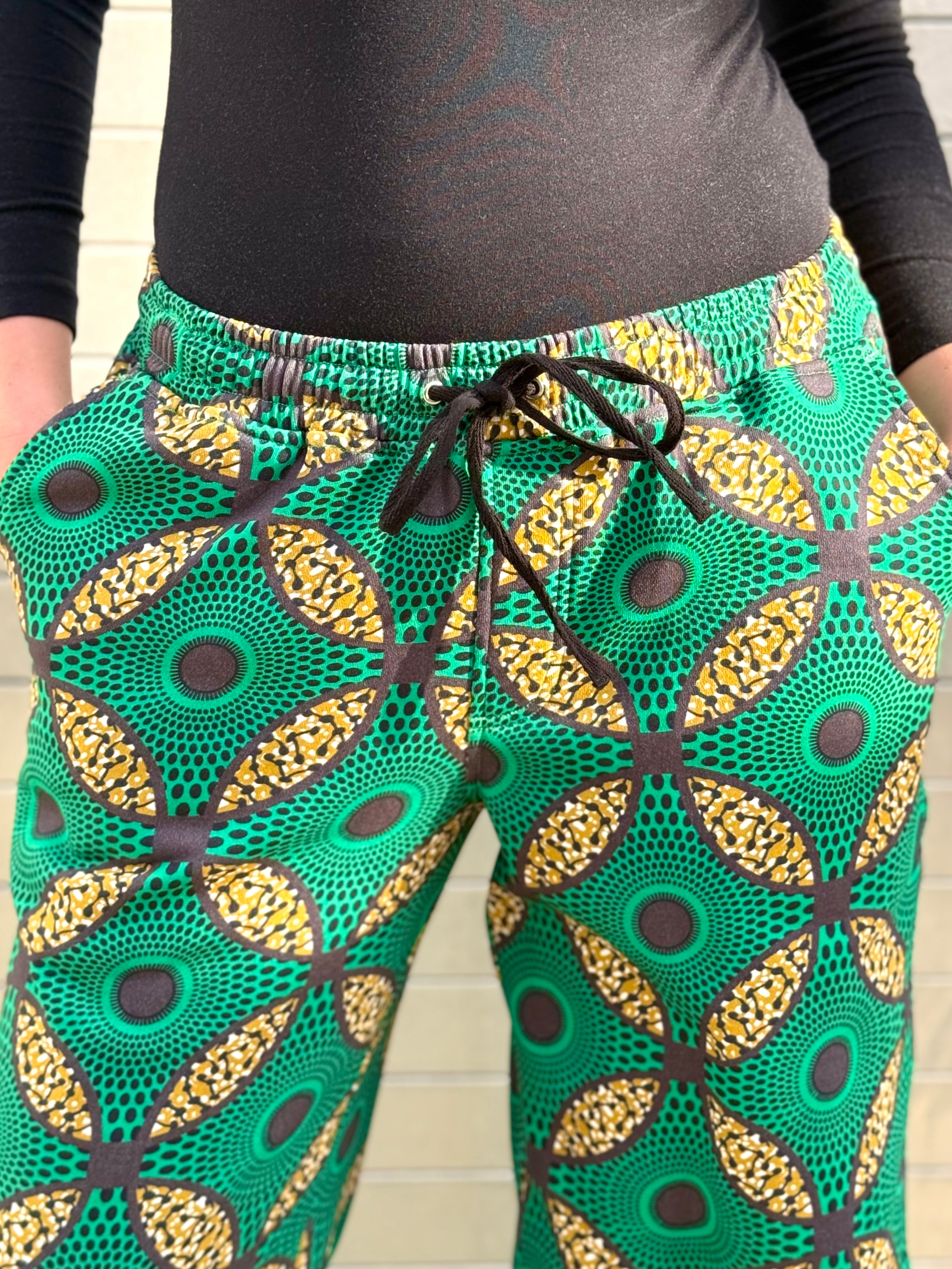 Front waistband close-up of the Ìmọ̀lẹ̀ Green Sweat Pants, featuring organic cotton texture and golden motifs. A celebration of sustainable comfort and artistic expression.