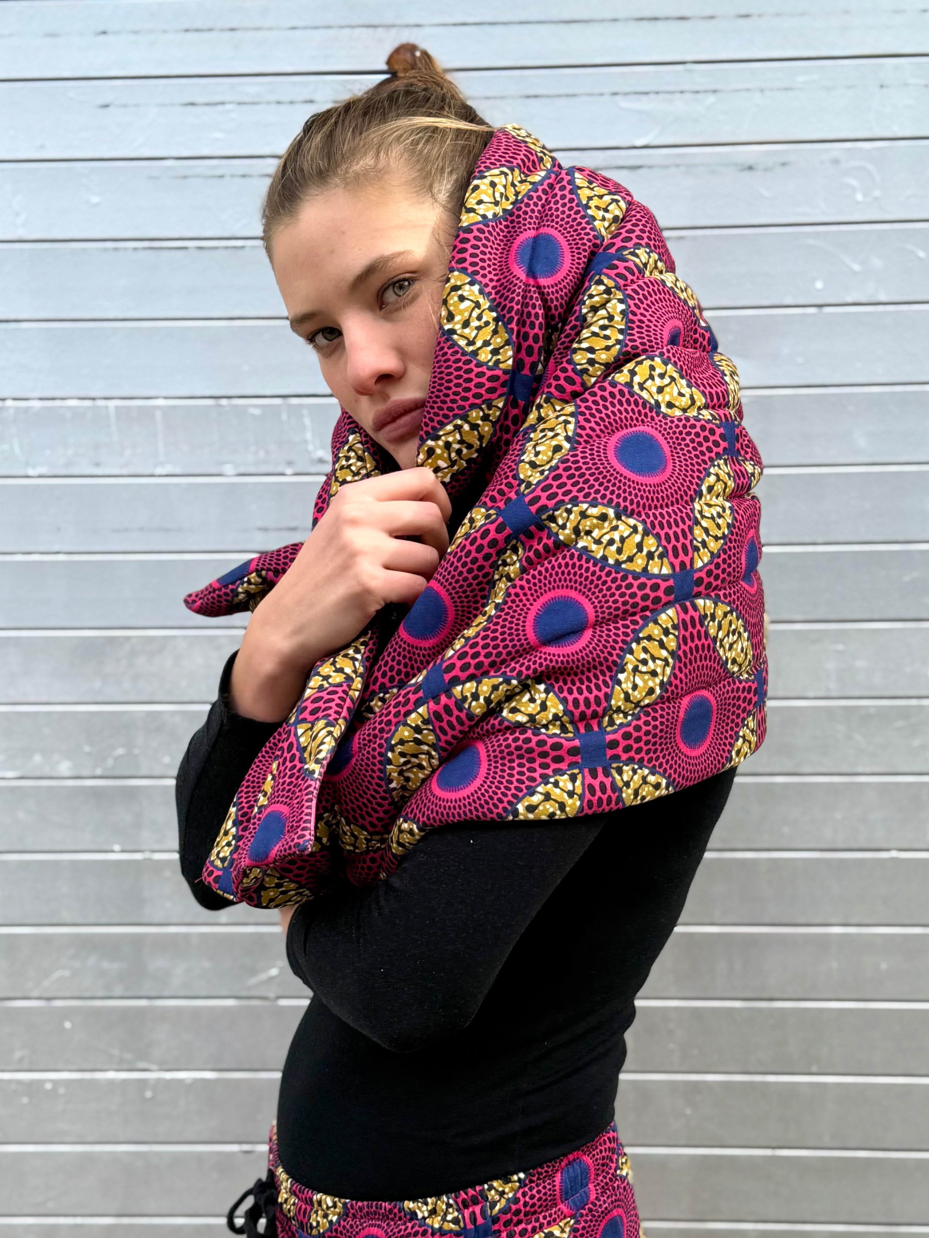 Model wearing the Ìmọ́lẹ̀ Pink Padded Sweat Scarf by Lola Faturoti Loves, crafted from organic cotton with Yoruba-inspired motifs that celebrate empowerment, color, and sustainability. Discover this sustainable padded wrap handcrafted with women artisans, merging African heritage, warmth, and modern self-expression.
