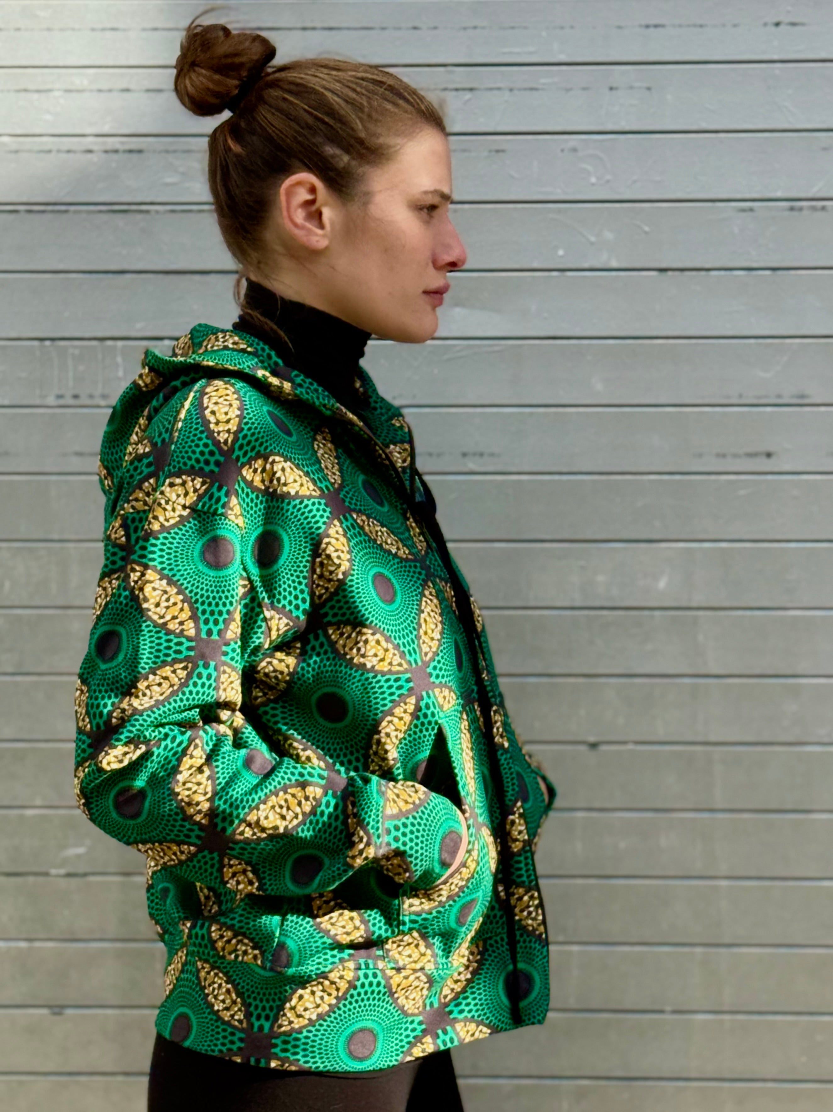 Profile shot of the Ìmọ́lẹ̀ Green Zip-Up Hoodie, featuring a clean cut and detailed Yoruba-inspired motifs. Sustainably made with organic cotton and eco-friendly inks, it’s a statement of warmth, artistry, and purpose.